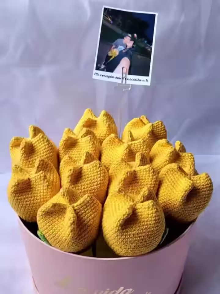 Florero con forma de cilindro con un hermoso ramo de tulipanes tejidos a crochet de diversos colores