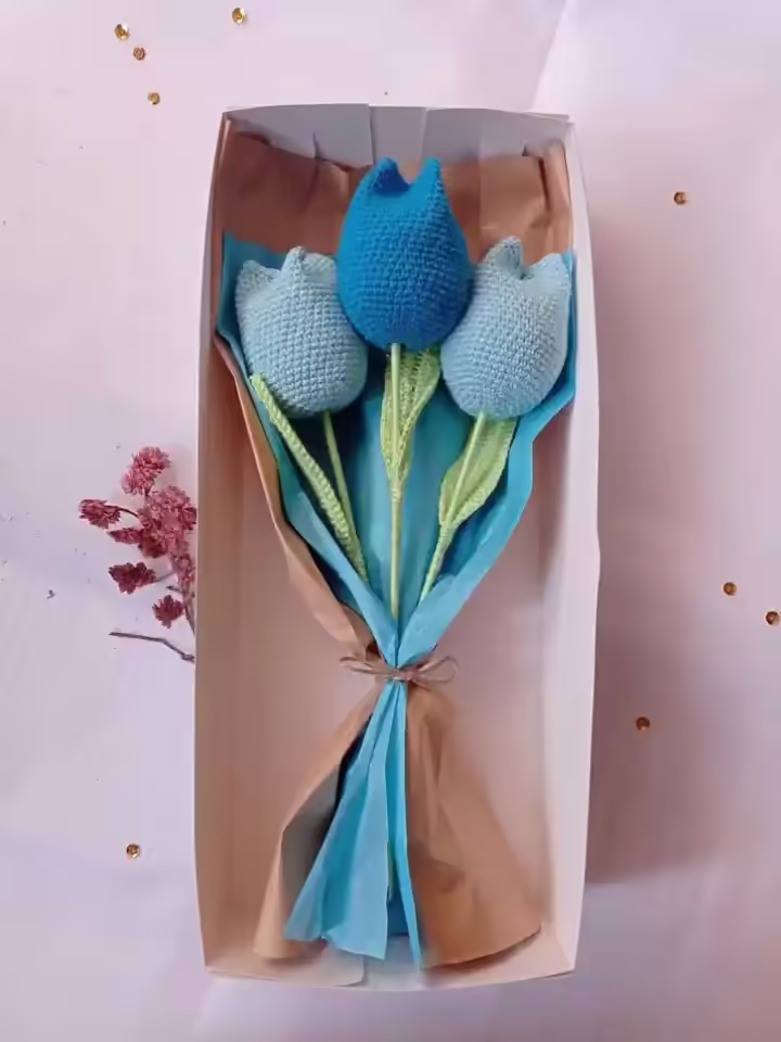 Una caja de regalo con tres tulipanes tejidos a crochet