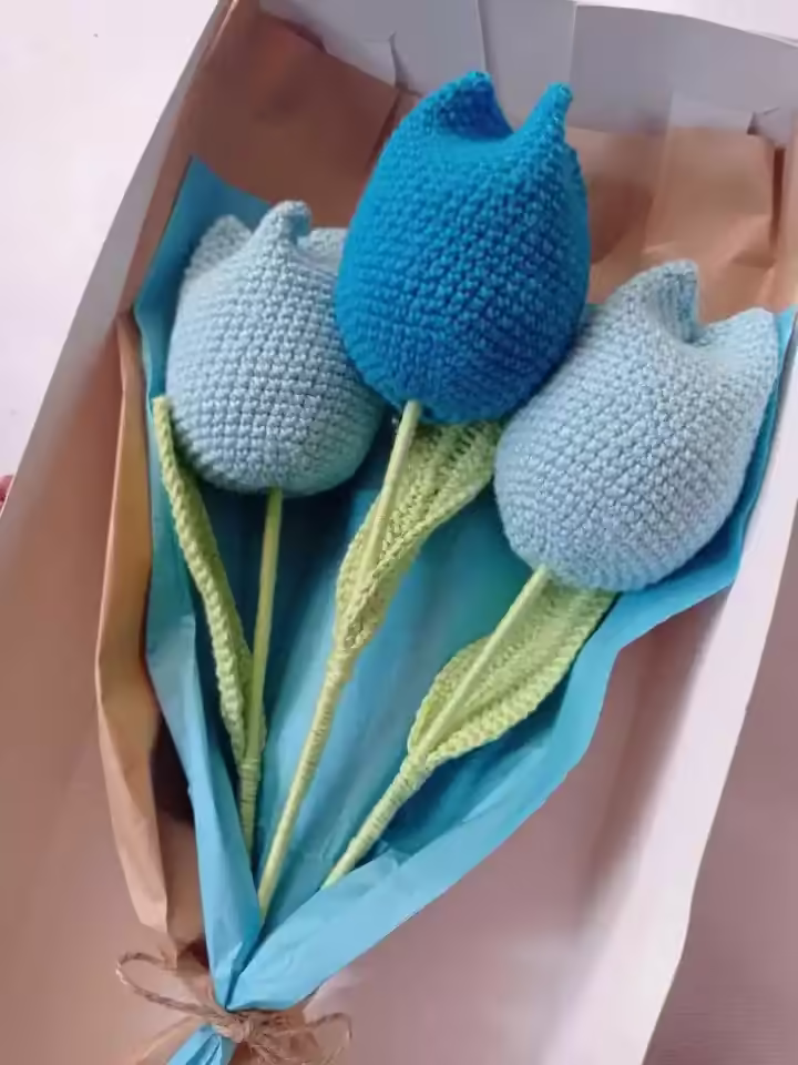 Una caja de regalo con tres tulipanes tejidos a crochet