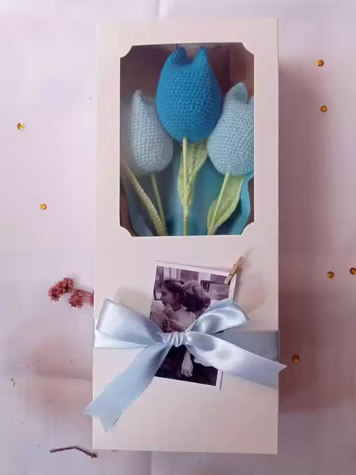 Una caja de regalo con tres tulipanes tejidos a crochet, con un lazo y una foto polaroid personalizable
